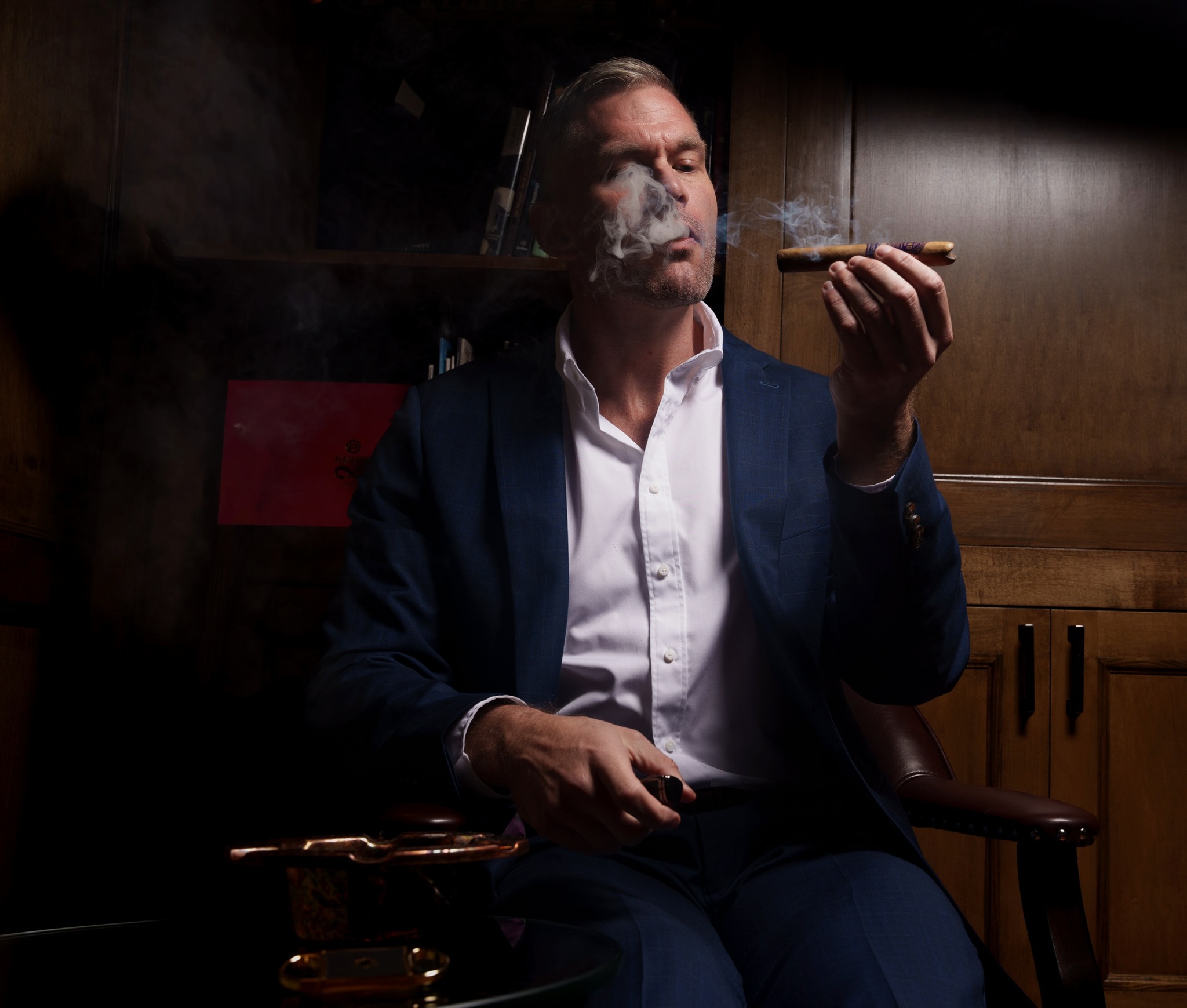 Drew Fowler exhaling cigar smoke, seated and relaxed