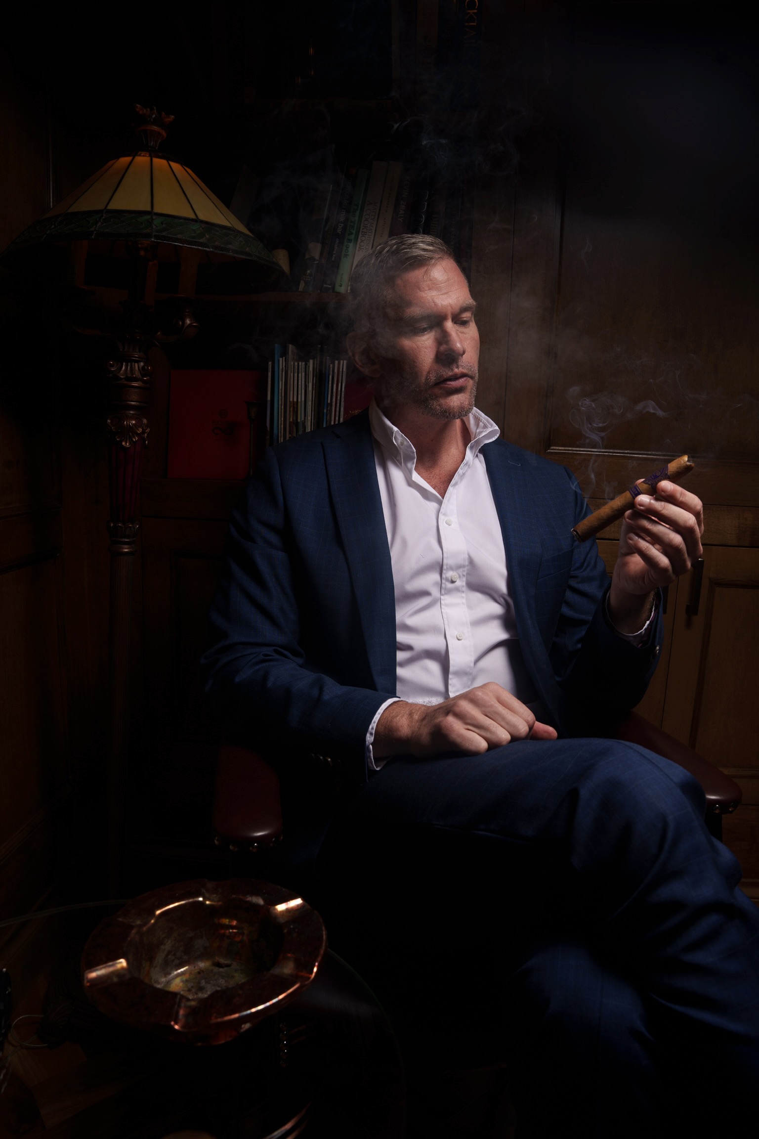 Drew Fowler seated with eyes closed, holding a cigar
