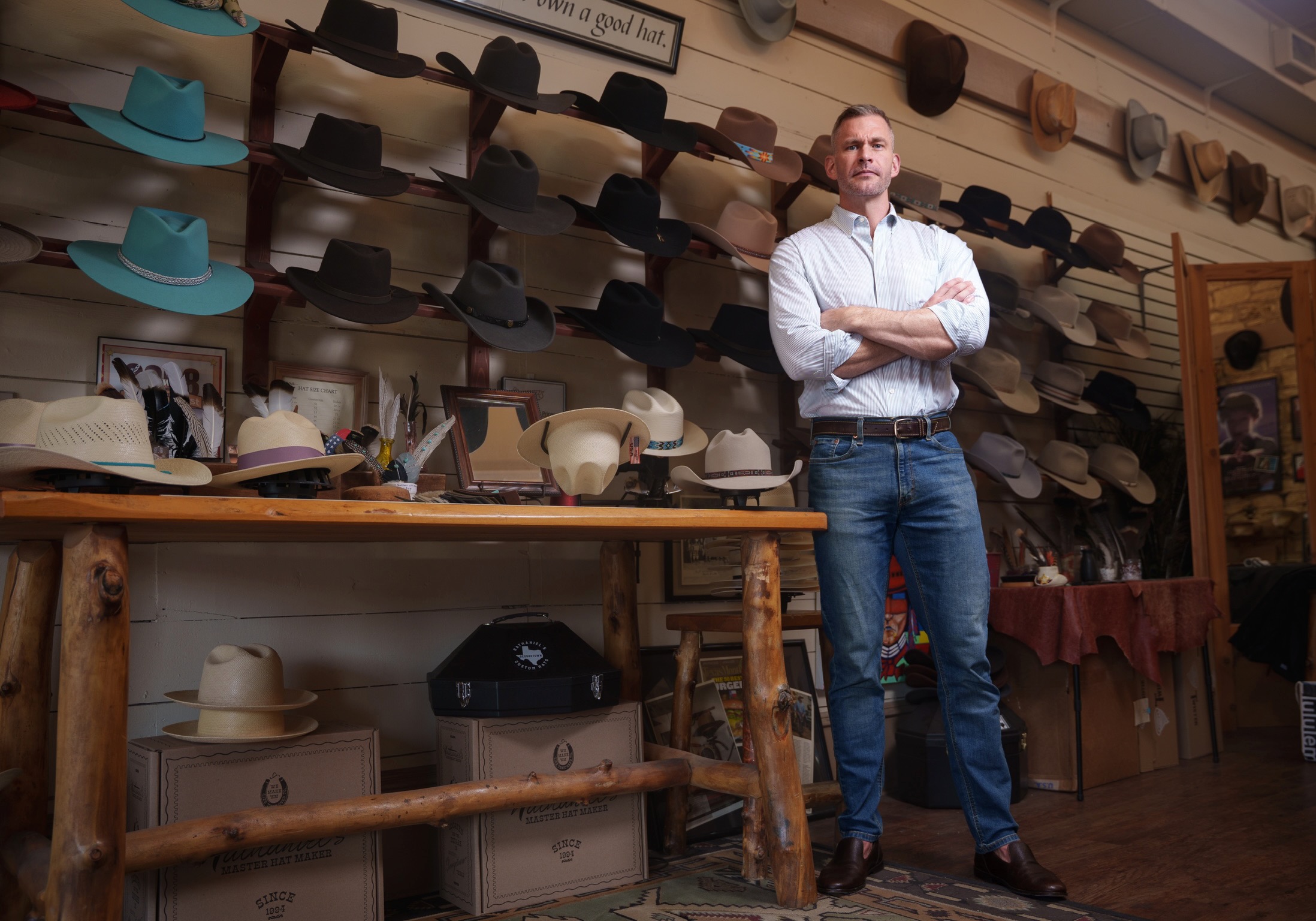 Drew Fowler standing in front of a hat wall
