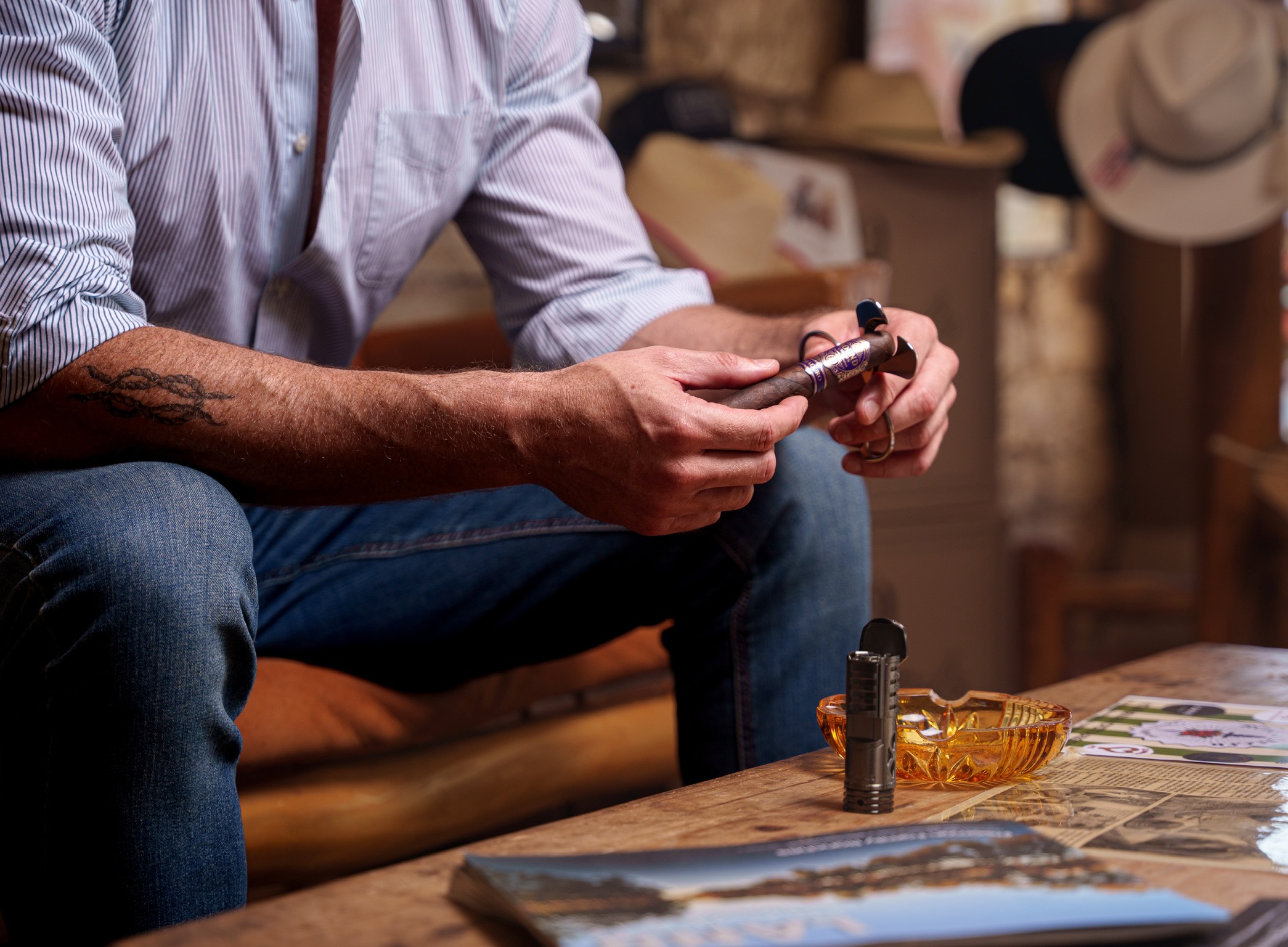 Hands cutting a Bound cigar, forearm tattoo visible