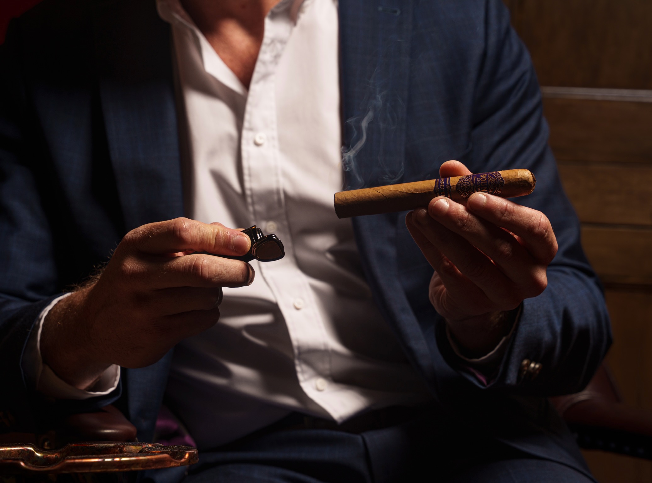 Hands holding a lit Bound cigar and a cutter