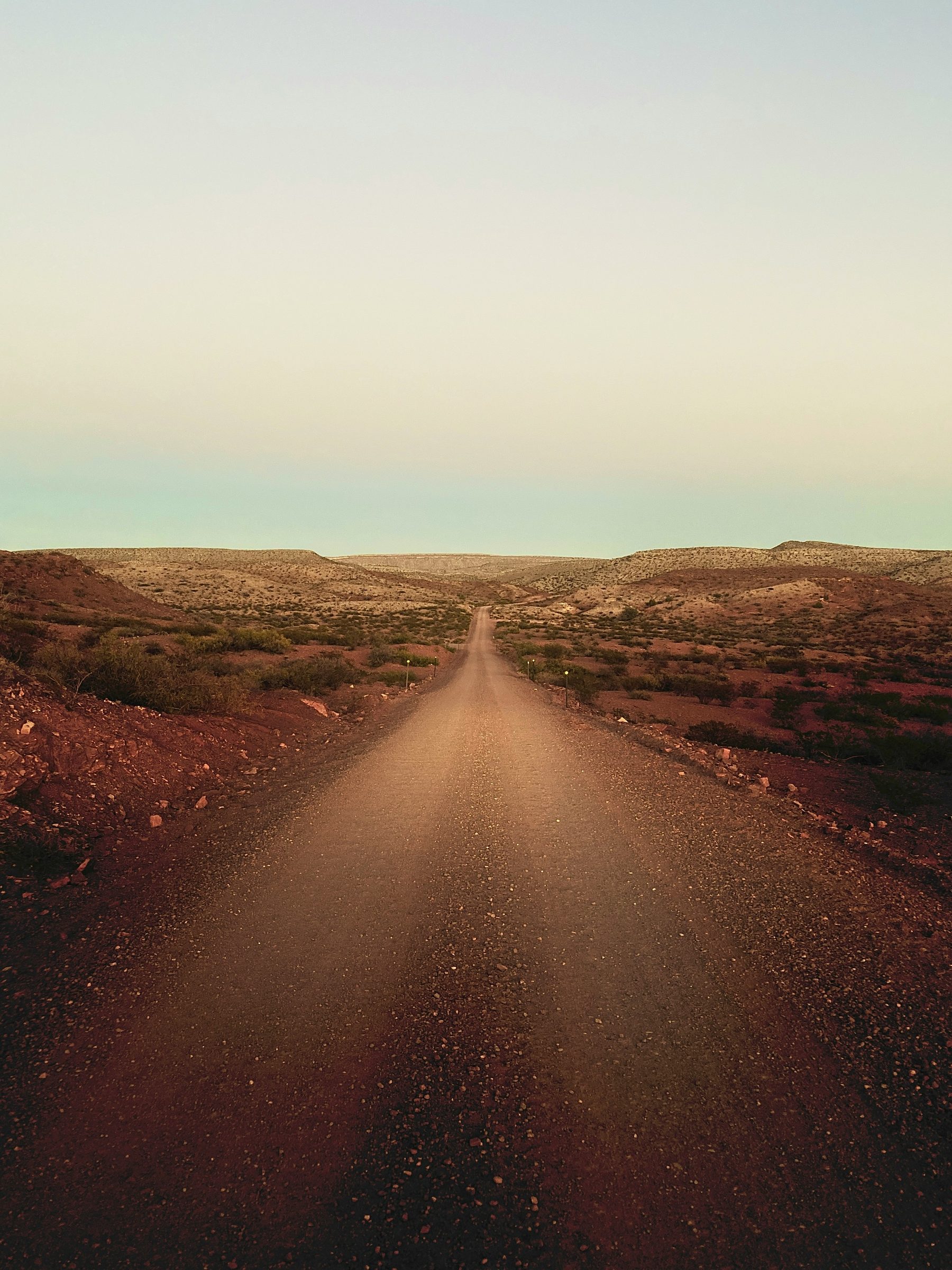 An empty desert road running toward the horizon