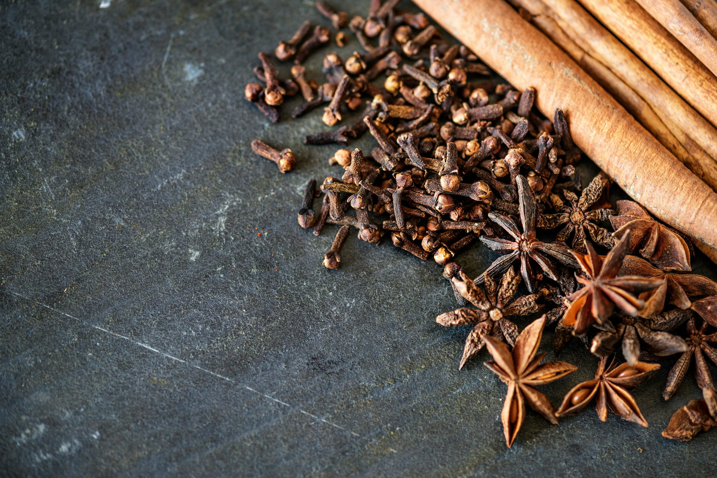 Cloves, star anise and cinnamon on dark slate