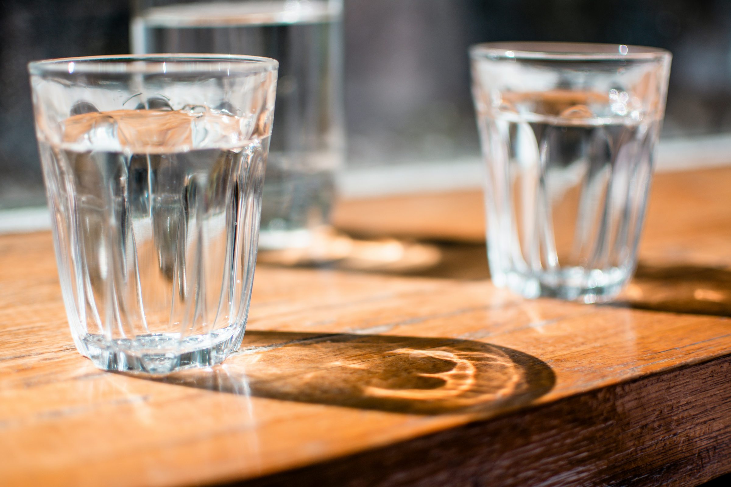 Two glasses of water on a wooden bar